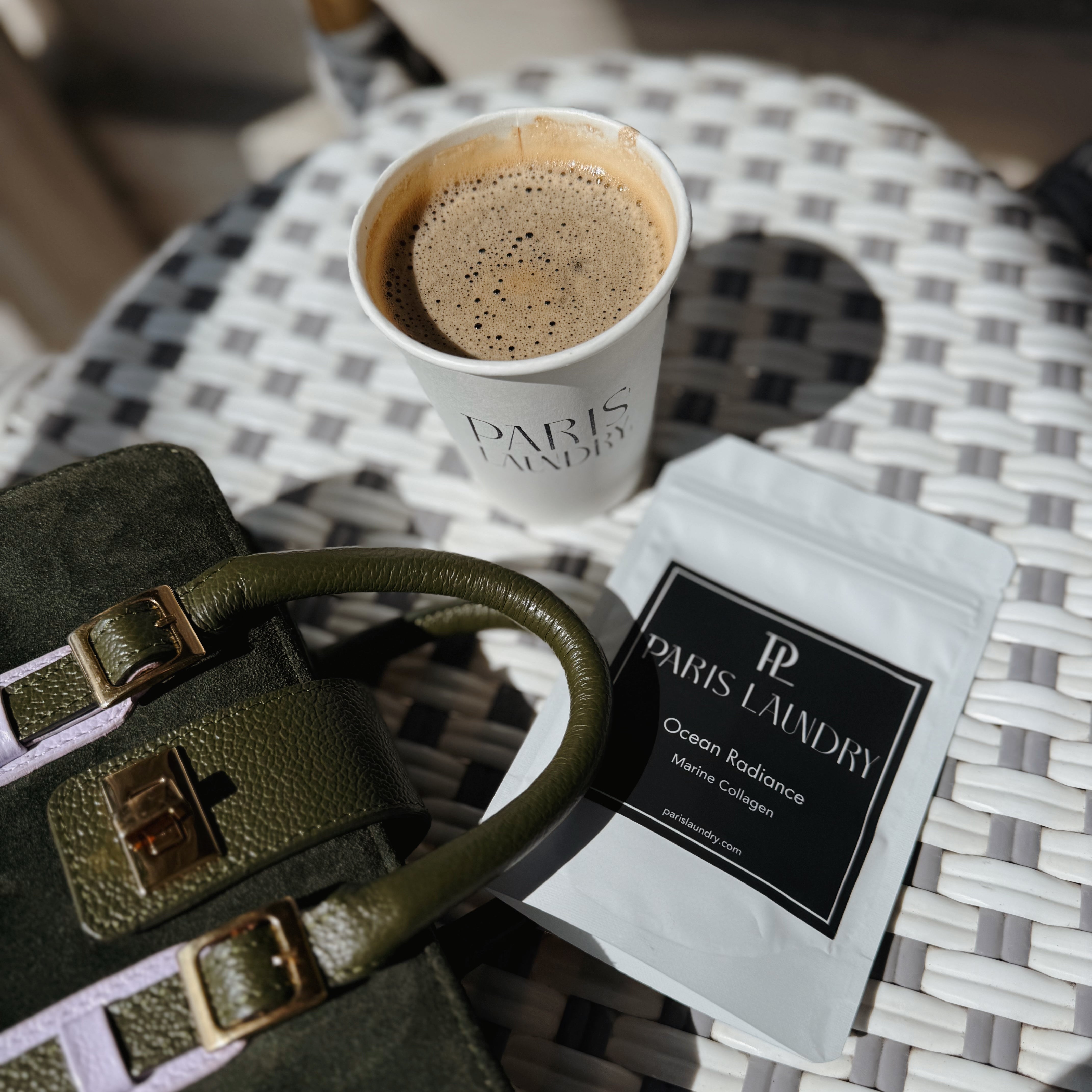 Green bag, coffee cup, and package on a checkered table