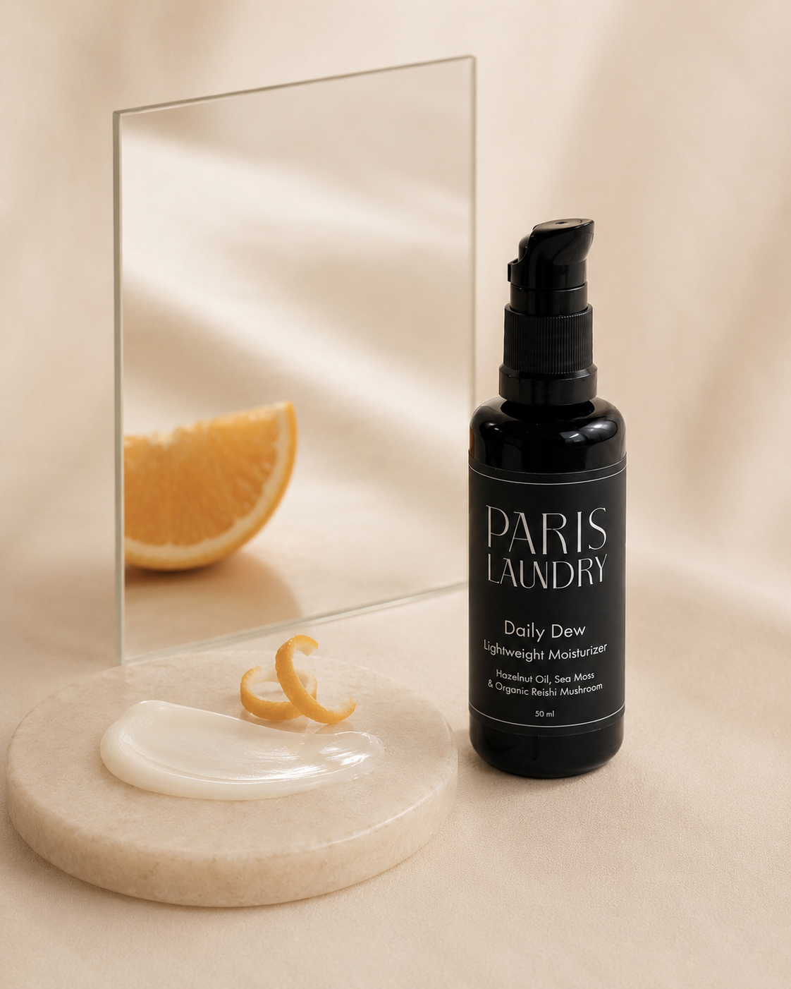 Black bottle of Paris Laundry skincare product on a beige surface with a mirror and orange slice.